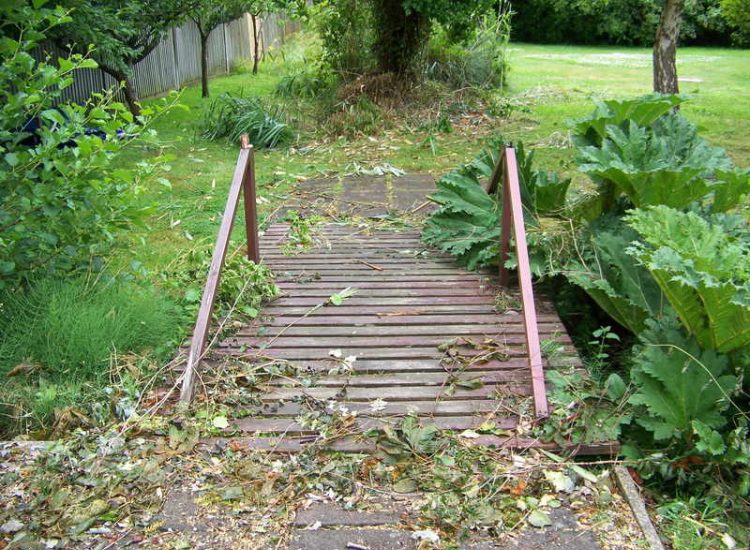 Garden Drainage and Brook Management Worplesdon, Guildford, Surrey - An existing brook had become over grown and blocked with vegetation and silt build up. Brook was cleared, re-ditched, a new under ground pipe installed, surrounding banks and lawns re-turfed and finally construction of a new Oak sleeper bridge to replace the old one. Garden Drainage - MDB Landscapes