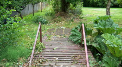 Garden Drainage and Brook Management Worplesdon, Guildford, Surrey - An existing brook had become over grown and blocked with vegetation and silt build up. Brook was cleared, re-ditched, a new under ground pipe installed, surrounding banks and lawns re-turfed and finally construction of a new Oak sleeper bridge to replace the old one. Garden Drainage - MDB Landscapes