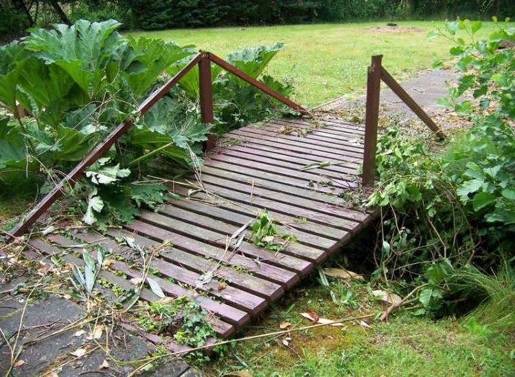 Garden Drainage and Brook Management Worplesdon, Guildford, Surrey - An existing brook had become over grown and blocked with vegetation and silt build up. Brook was cleared, re-ditched, a new under ground pipe installed, surrounding banks and lawns re-turfed and finally construction of a new Oak sleeper bridge to replace the old one. Garden Drainage - MDB Landscapes