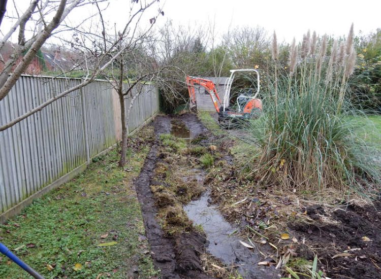 Garden Drainage and Brook Management Worplesdon, Guildford, Surrey - An existing brook had become over grown and blocked with vegetation and silt build up. Brook was cleared, re-ditched, a new under ground pipe installed, surrounding banks and lawns re-turfed and finally construction of a new Oak sleeper bridge to replace the old one. Garden Drainage - MDB Landscapes