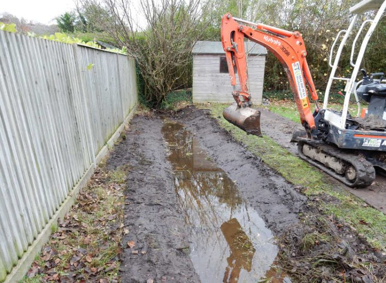Garden Drainage and Brook Management Worplesdon, Guildford, Surrey - An existing brook had become over grown and blocked with vegetation and silt build up. Brook was cleared, re-ditched, a new under ground pipe installed, surrounding banks and lawns re-turfed and finally construction of a new Oak sleeper bridge to replace the old one. Garden Drainage - MDB Landscapes