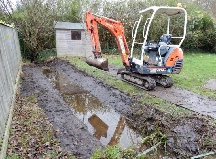 Garden Drainage and Brook Management Worplesdon, Guildford, Surrey - An existing brook had become over grown and blocked with vegetation and silt build up. Brook was cleared, re-ditched, a new under ground pipe installed, surrounding banks and lawns re-turfed and finally construction of a new Oak sleeper bridge to replace the old one. Garden Drainage - MDB Landscapes