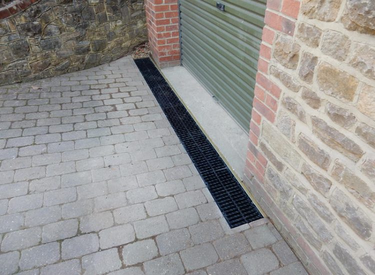 Driveway Drainage Farnham, Surrey - To help prevent further flooding of their garage the existing poor drainage infront of the garage was replaced with wide cast iron grated linear drainage channels. Garden Drainage - MDB Landscapes