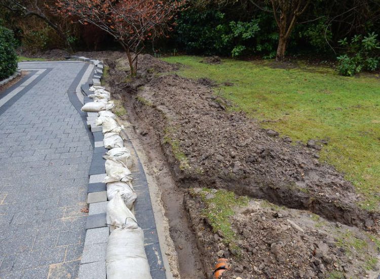 Driveway Drainage Ottershaw, Surrey - Linear drainage with cast iron gratings were proposed here to help prevent the constant threat of flooding from run off from the road. Water was diverted through large diamater pipe work and land drainage finaly being dispersed at the bottom of the garden. Garden Drainage - MDB Landscapes
