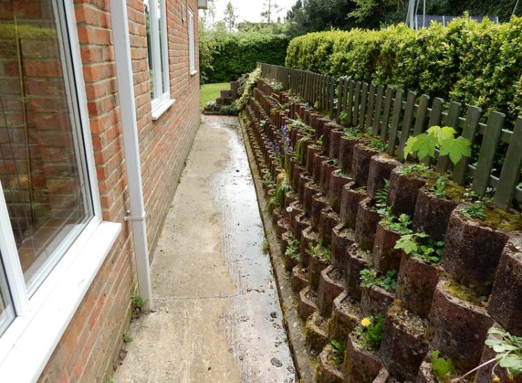 Garden Drainage Farnham, Surrey - Trapped water behind retaining walls was constantly seeping through flooding areas around the house. The most cost effective solution for the client was to catch the flow of water house side of retaining wall and divert it into a brook. Garden Drainage -MDB Landscapes
