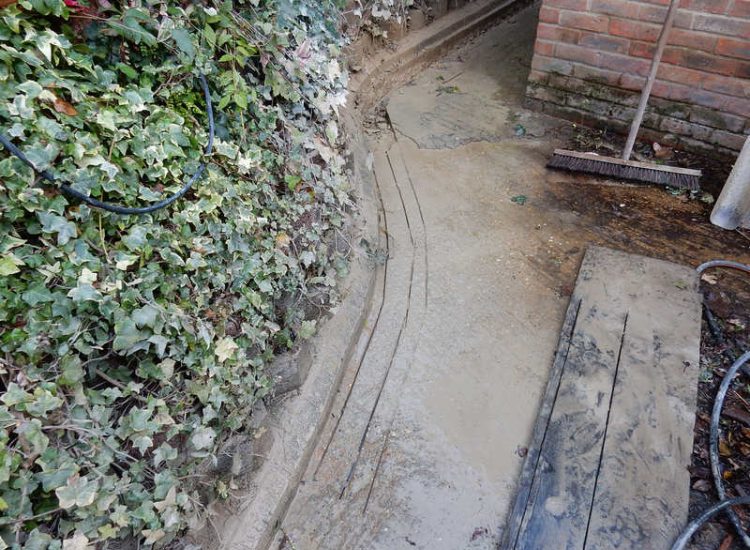 Garden Drainage Farnham, Surrey - Trapped water behind retaining walls was constantly seeping through flooding areas around the house. The most cost effective solution for the client was to catch the flow of water house side of retaining wall and divert it into a brook. Garden Drainage -MDB Landscapes