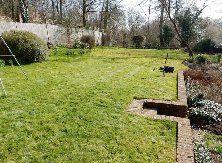 Lawn Drainage Crondall, Hampshire - A substantial lawn area suffering from water ingress from highr ground. Land drainage was installed with drainage trenches re-turfed. The outlet point here was lower ground within a wooded area. Garden Drainage - MDB Landscapes