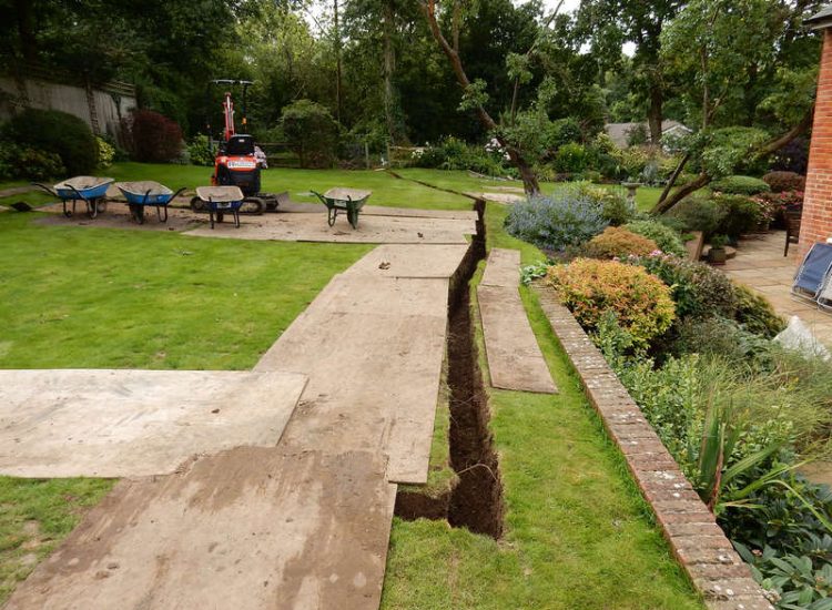 Lawn Drainage Crondall, Hampshire - A substantial lawn area suffering from water ingress from highr ground. Land drainage was installed with drainage trenches re-turfed. The outlet point here was lower ground within a wooded area. Garden Drainage - MDB Landscapes