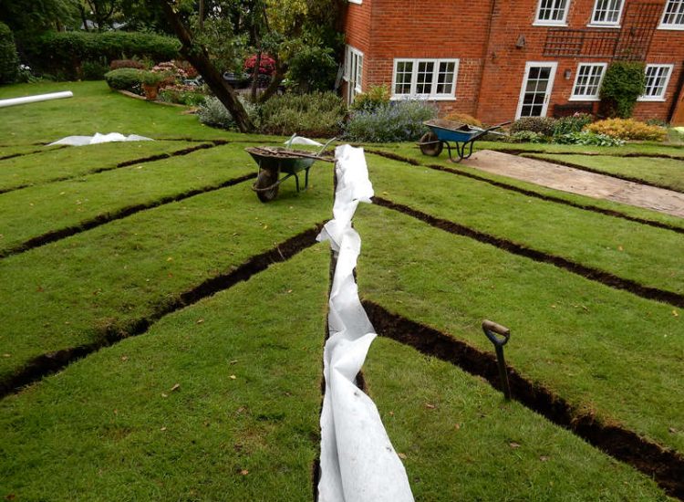 Lawn Drainage Crondall, Hampshire - A substantial lawn area suffering from water ingress from highr ground. Land drainage was installed with drainage trenches re-turfed. The outlet point here was lower ground within a wooded area. Garden Drainage - MDB Landscapes