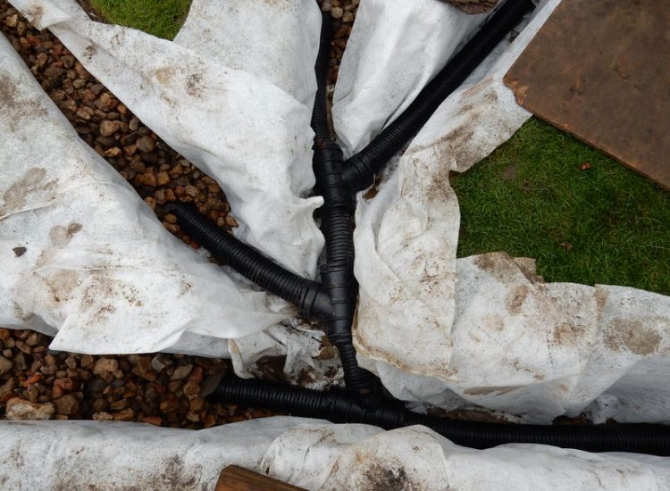 Lawn Drainage Crondall, Hampshire - A substantial lawn area suffering from water ingress from highr ground. Land drainage was installed with drainage trenches re-turfed. The outlet point here was lower ground within a wooded area. Garden Drainage - MDB Landscapes