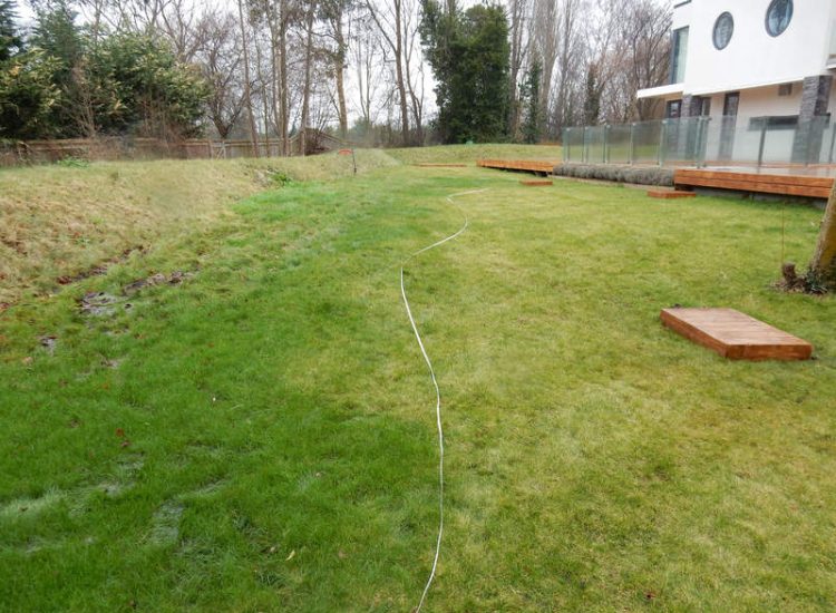Lawn Drainage Hersham, Surrey - Building works had left an area of the garden in poor state, compacted with buried waste materials. There was also an added issue of Constant water ingress from an unknown source. Levels were reduced first, drainage installed using the river as an outlet source, topsoil spread and grass seeded on completion. Garden Drainage - MDB Landscapes