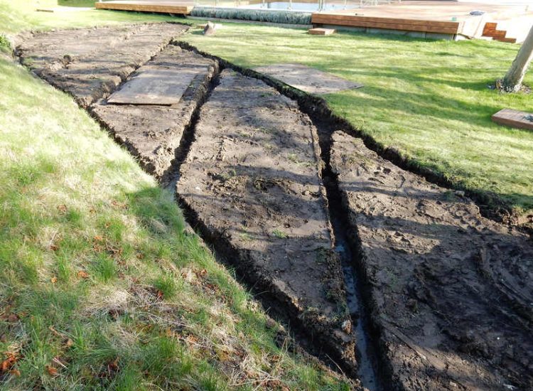 Lawn Drainage Hersham, Surrey - Building works had left an area of the garden in poor state, compacted with buried waste materials. There was also an added issue of Constant water ingress from an unknown source. Levels were reduced first, drainage installed using the river as an outlet source, topsoil spread and grass seeded on completion. Garden Drainage - MDB Landscapes