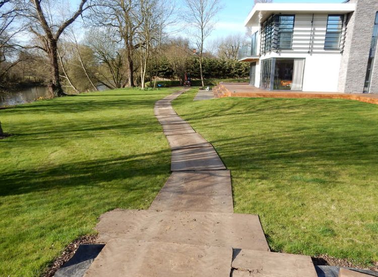Lawn Drainage Hersham, Surrey - Building works had left an area of the garden in poor state, compacted with buried waste materials. There was also an added issue of Constant water ingress from an unknown source. Levels were reduced first, drainage installed using the river as an outlet source, topsoil spread and grass seeded on completion. Garden Drainage - MDB Landscapes